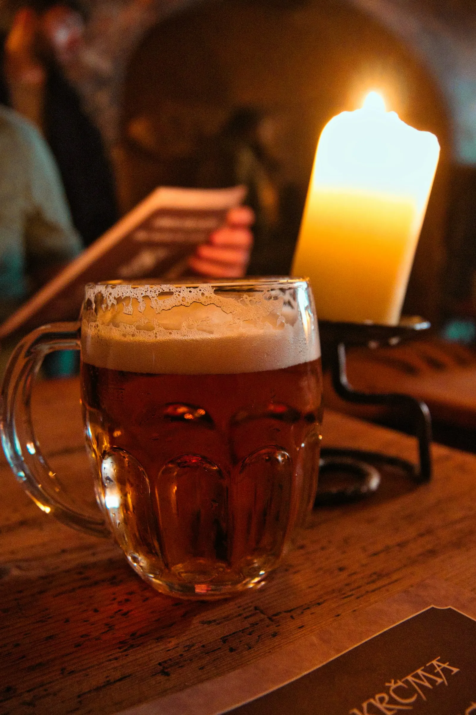 Et glass øl ved et stearinlys på et trebord
